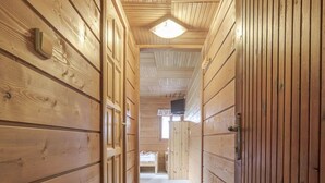 Un passadís de fusta amb terra endollida i una porta al final.
