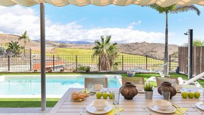 A dining table set for two with a view of a pool and mountains in the background.