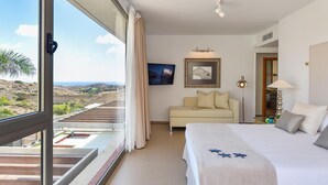A hotel room with a balcony, a bed, a sofa, and a view of the landscape.