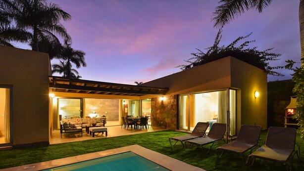 Une maison moderne dotée d’une piscine, d’un espace salon extérieur et d’un patio.