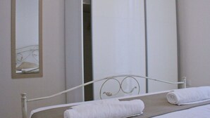 Een slaapkamer met een bed, een spiegel en een kledingkast.