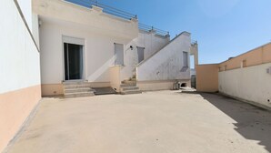 Un edificio residencial con techo plano y una escalera que lleva a la entrada, bajo un cielo despejado.