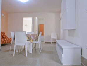 A room with a dining table, chairs, a sofa, and a TV stand.