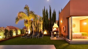 A modern outdoor area with a pool, lounge chairs, and a barbecue grill.