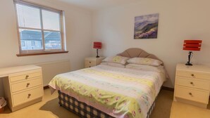 A bedroom with a bed, two bedside tables, a window, and a painting on the wall. - Lovely apartment for 4 people with TV and terrace (Inverness)