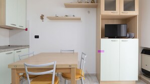 A compact kitchen with a dining table, chairs, and a TV on a cabinet. - Cosy apartment for 4 guests with A/C, WIFI, TV, balcony and pets allowed (Diano Marina)