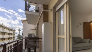 A balcony with a wooden chair, a small table, and a trash bin. - Cosy apartment for 4 guests with A/C, WIFI, TV, balcony and pets allowed (Diano Marina)
