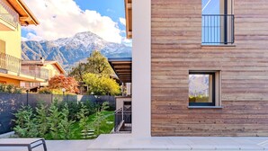 A modern pool area with a wooden deck, a pool, and a view of mountains in the background. - Stunning private villa for 10 guests with A/C, WIFI, private pool, terrace and pets allowed (Colico)