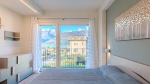 A bedroom with a large bed, a view of mountains, a balcony with a railing, and a painting on the wall. - Stunning private villa for 10 guests with A/C, WIFI, private pool, terrace and pets allowed (Colico)