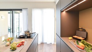 A modern kitchen with a large island, a built-in oven, and a microwave. There are fresh vegetables on the island, and a window with curtains in the background. - Beautiful private villa for 6 people with A/C, WIFI, pool, TV, patio and pets allowed (Maspalomas)