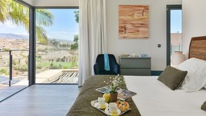A modern hotel room with a large bed, a dining area with a tray of breakfast, a chair, and a view of the desert landscape. - Beautiful private villa for 6 people with A/C, WIFI, pool, TV, patio and pets allowed (Maspalomas)