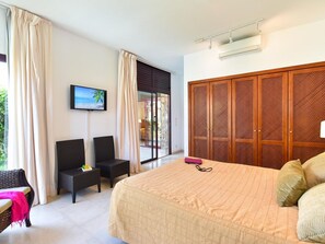 Een hotelkamer met een bed, een televisie, een zithoek met stoelen en een grote houten garderobe.