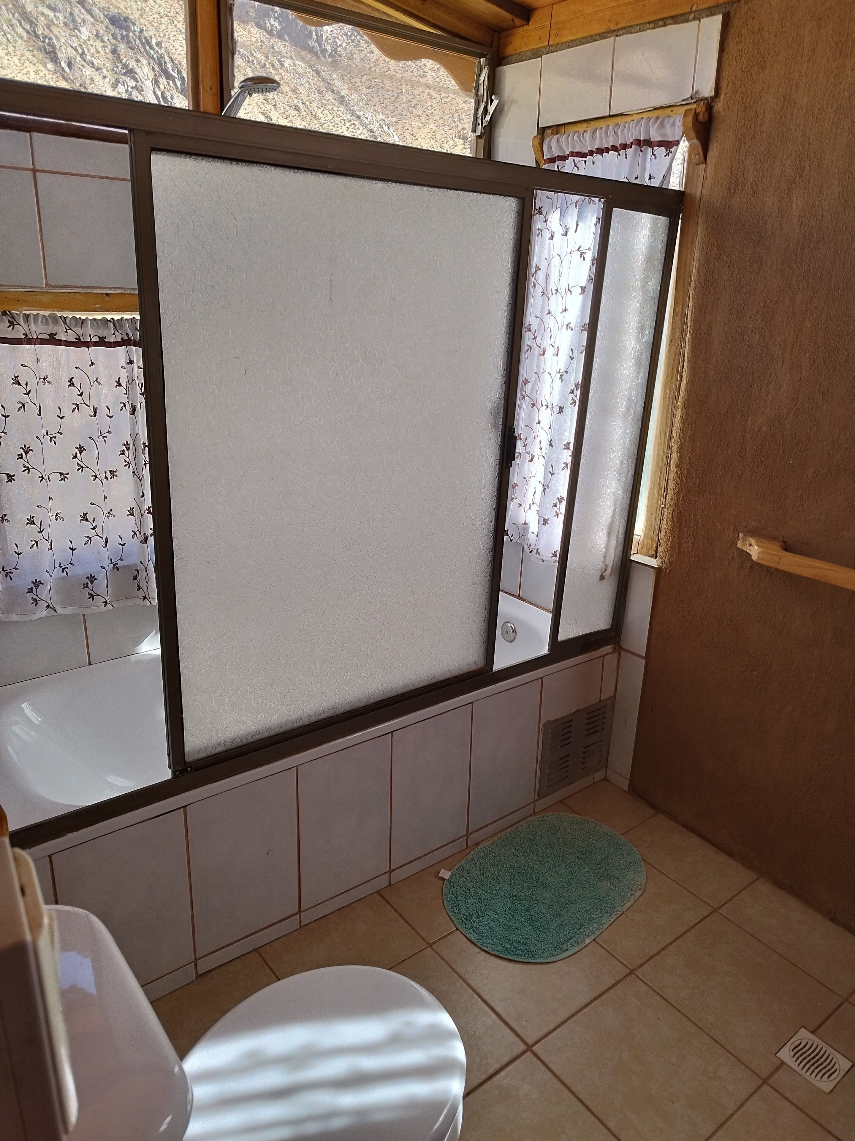 Un baño con inodoro, lavabo y ventana con cortinas estampadas.