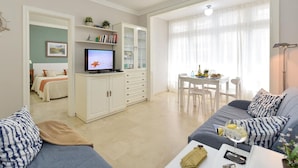Una sala de estar moderna con sofá, televisión, comedor y cocina.
