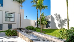 A modern building with a stone water feature, palm trees, and a well-maintained lawn. - Stunning  villa for 6 guests with WIFI, pool, A/C, TV and terrace (Nerja)