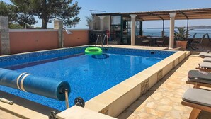 A swimming pool with a blue mosaic tile border, a green inflatable ring, and a water filtration system. - Nice apartment in Privlaka (Privlaka)