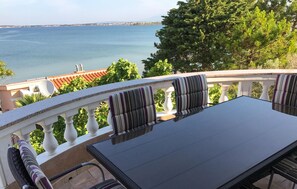 Un balcón con una mesa y sillas, con vistas a una masa de agua y una costa distante.