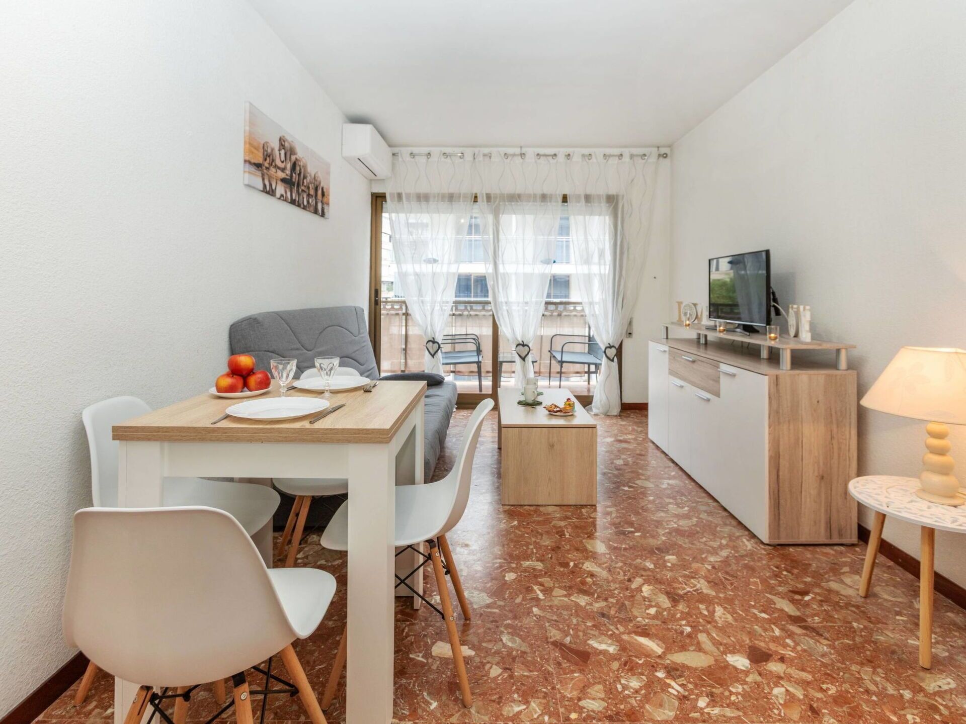 Un espace de vie compact comprenant un coin repas, un canapé, un téléviseur et un coin cuisine.
