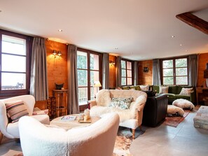 Un salon chaleureux avec une cheminée, des murs en bois et de grandes fenêtres.