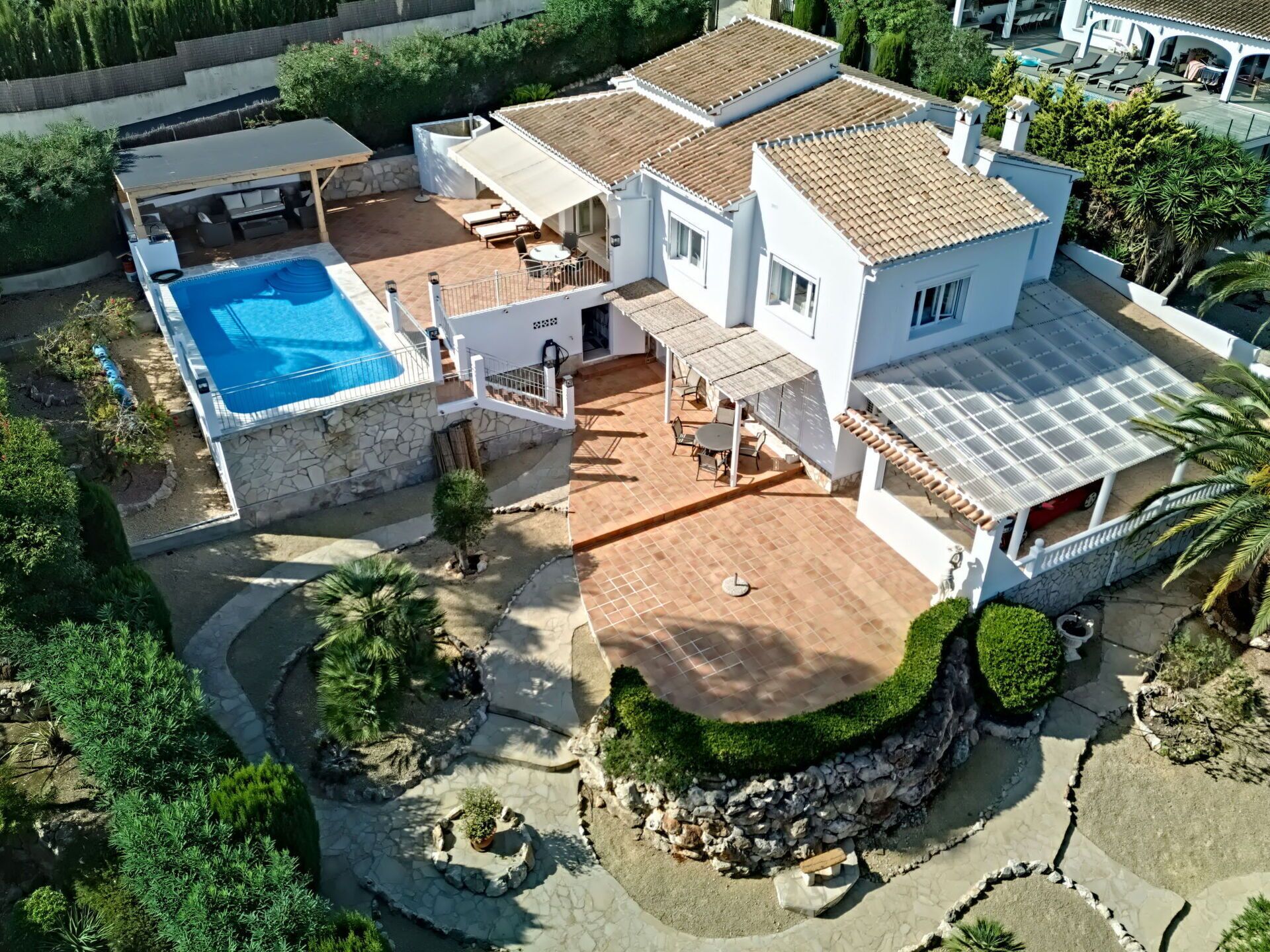 A two-story house with a swimming pool, patio, and garden.