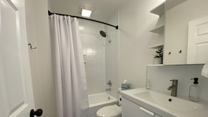 Un baño moderno con ducha, inodoro, lavamanos y armarios para almacenamiento.