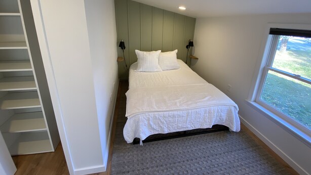 A bedroom with a bed, a window, a door, and a staircase. - Cute centrally located home! (Cedar Falls)
