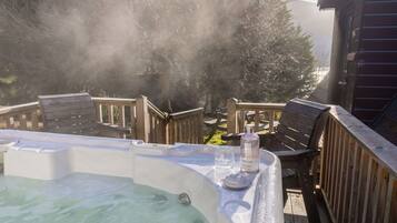 Relax in the hot tub surrounded by a serene forest view.