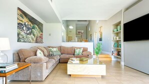A modern living room with a sectional sofa, a coffee table, and a flat-screen TV.