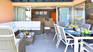 A modern outdoor living area with a sofa, dining table, and chairs.