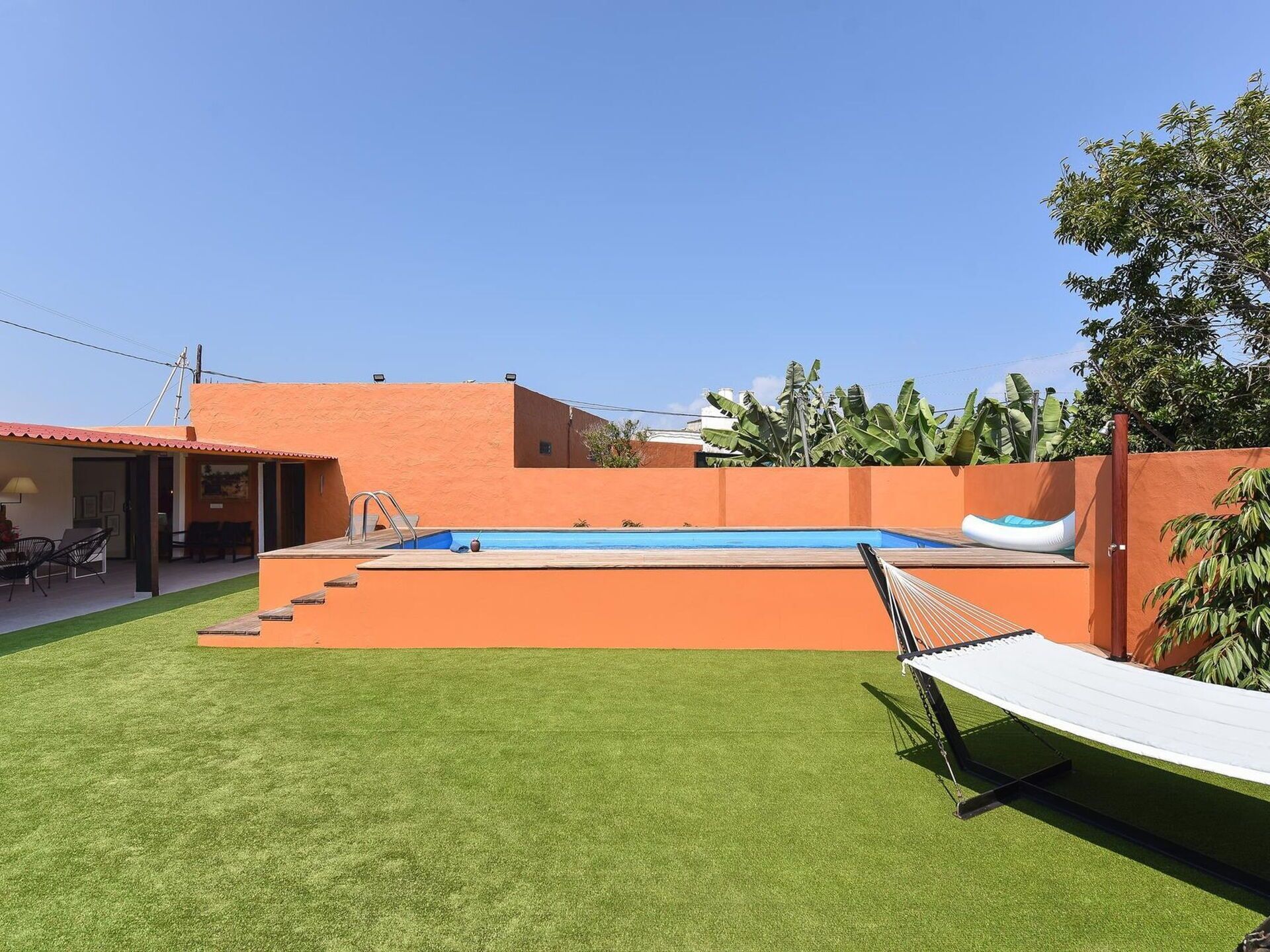 A swimming pool with a slide, a hammock, and a covered seating area.