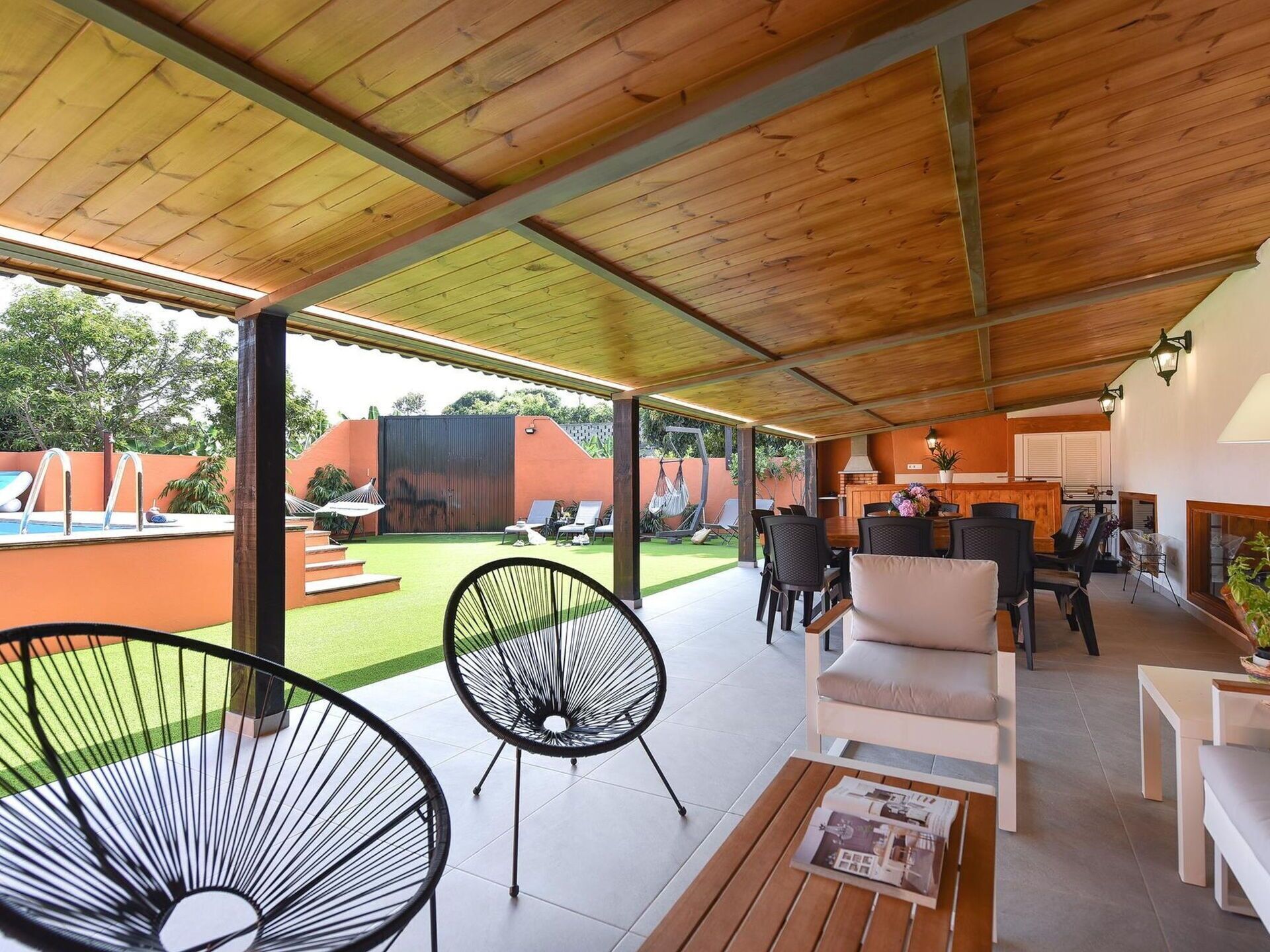 Un espace de vie extérieur abrité, doté d’une piscine, de chaises longues et d’un coin repas.