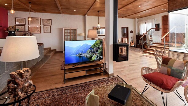 A spacious living room with a wooden ceiling, a flat-screen TV, a fireplace, and a view of a mountain landscape. - Beautiful private villa for 10 guests with WIFI, private pool, TV and patio (Arucas)