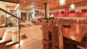 A spacious dining area with wooden tables and chairs, a staircase leading to another level, and a view of the kitchen area in the background. - Beautiful private villa for 10 guests with WIFI, private pool, TV and patio (Arucas)