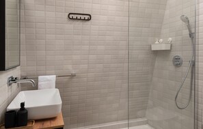 Bathroom features a pedestal sink, mirror, and glass-enclosed shower.