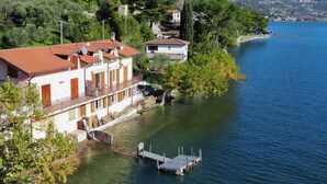 Une propriété au bord du lac, dotée d’un quai, d’un bâtiment à toit rouge et offrant une vue sur le lac et les collines environnantes.