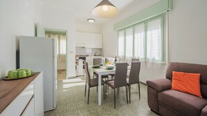 A compact kitchen with a dining area, a sofa, and a window with curtains. - Beautiful apartment for 6 guests with WIFI, TV and patio (Pietrasanta)