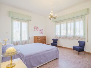 Un dormitorio con una cama, dos sillas, un aparador y una araña.
