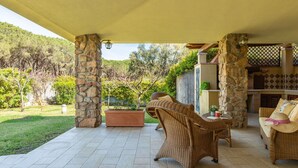 A covered patio with wicker furniture, stone pillars, and a view of the surrounding garden and hills. - Beautiful private villa for 4 people with WIFI, A/C, TV, terrace and panoramic view (Villasimius)