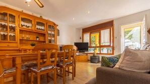 A cozy living room with wooden furniture, a television, and a window with curtains. - Wonderful private villa for 6 guests with WIFI, A/C, private pool, TV, patio and pets allowed (Deltebre)