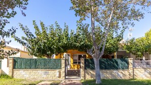 A pathway leading to a building with a stone wall and a green fence. - Wonderful private villa for 6 guests with WIFI, A/C, private pool, TV, patio and pets allowed (Deltebre)