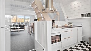 Eine moderne Küche mit einem zentralen Kamin, weißen Schränken und einem Schachbrettfußboden.