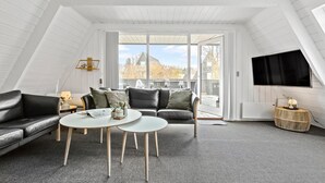 Ein modernes Schlafzimmer im Loft-Stil mit schrägen Wänden, einem großen Fenster, einem Flachbildfernseher, einer Couch, einem Couchtisch und einem kleinen Beistelltisch.