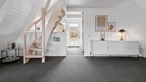 Ein modernes Interieur mit einer Holztreppe, einer weißen Konsole und gerahmten Kunstwerken an der Wand.