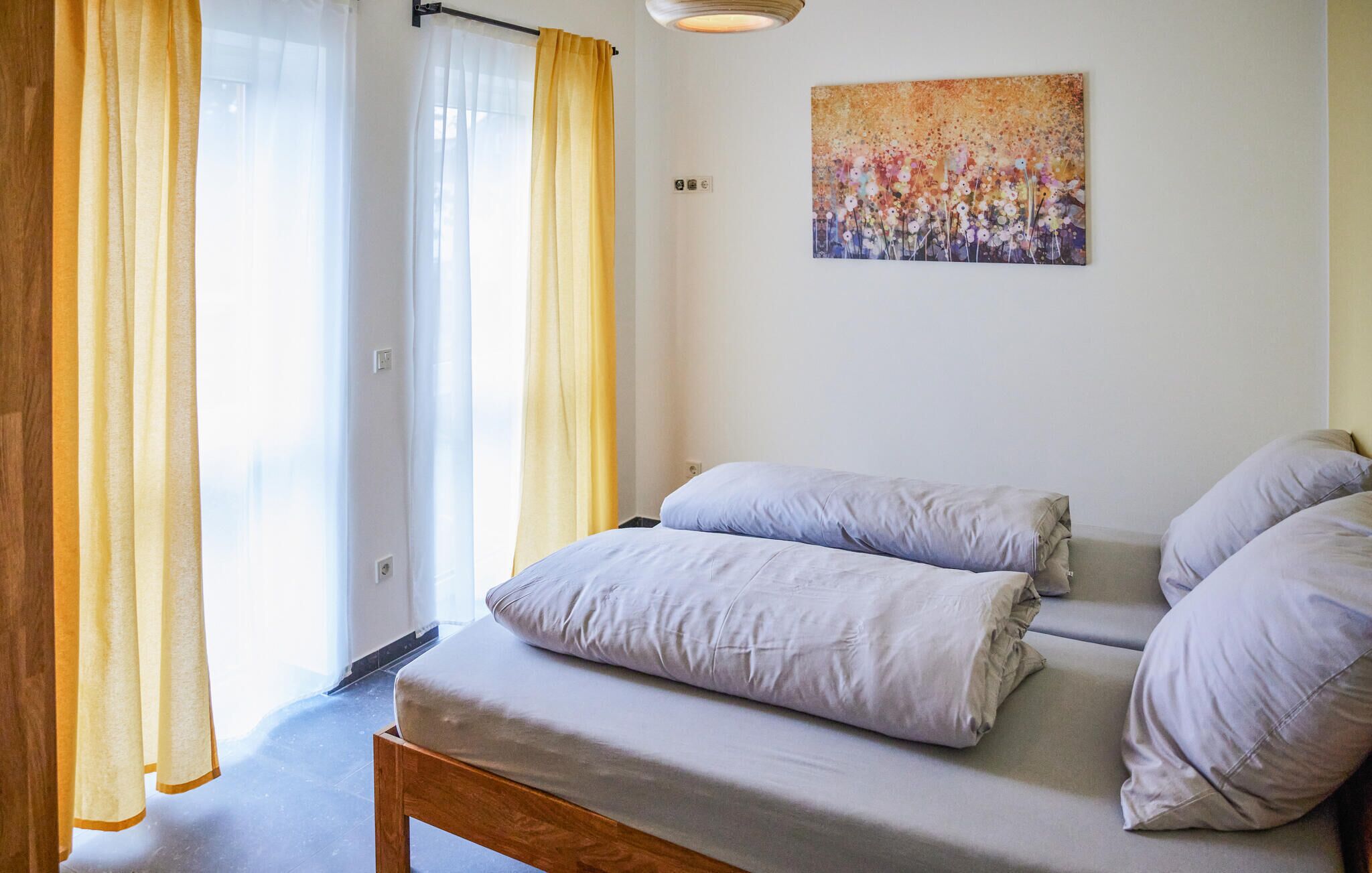 A bedroom with a bed, two pillows, a wooden bench, and a painting on the wall.