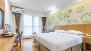 A hotel room with a bed, desk, chair, and a wall with circular patterns. - Greentree Inn Hefei Government Cultural District South District Provincial Hospital Nanqu Hotel (Hefei)