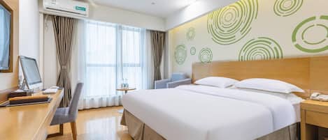 A hotel room with a bed, desk, chair, and a wall with circular patterns.