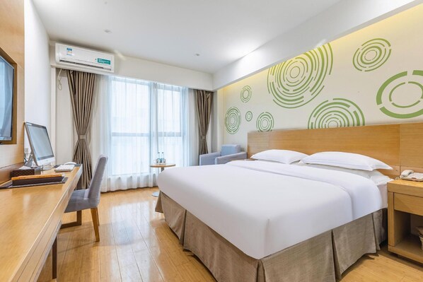 A hotel room with a bed, desk, chair, and a wall with circular patterns. - Greentree Inn Hefei Government Cultural District South District Provincial Hospital Nanqu Hotel (Hefei)