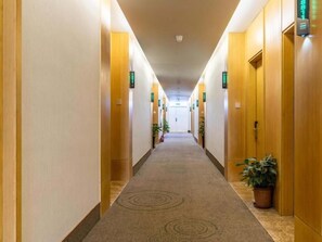 A hotel corridor with wooden walls, carpeted floor, and potted plants. - Greentree Inn Hefei Government Cultural District South District Provincial Hospital Nanqu Hotel (Hefei)