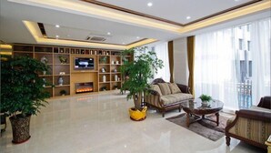 A modern living room with a sofa, coffee table, and a fireplace. There are shelves with decorative items and a television. - Greentree Inn Hefei Government Cultural District South District Provincial Hospital Nanqu Hotel (Hefei)