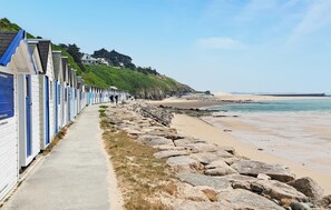 Une promenade en bord de mer, avec des cabanes de plage et une côte rocheuse.